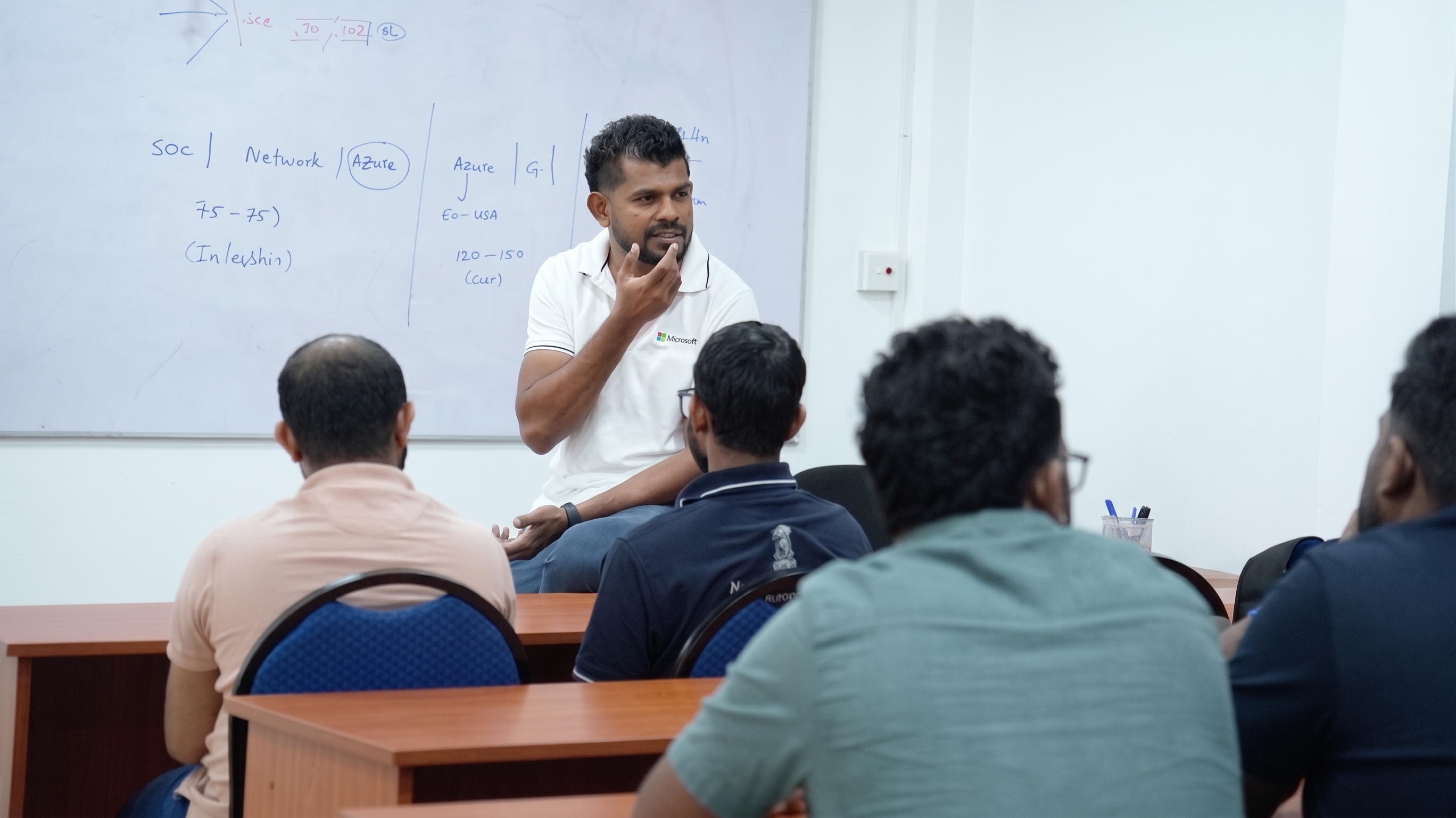 Instructor discussing technology topics with students in a classroom