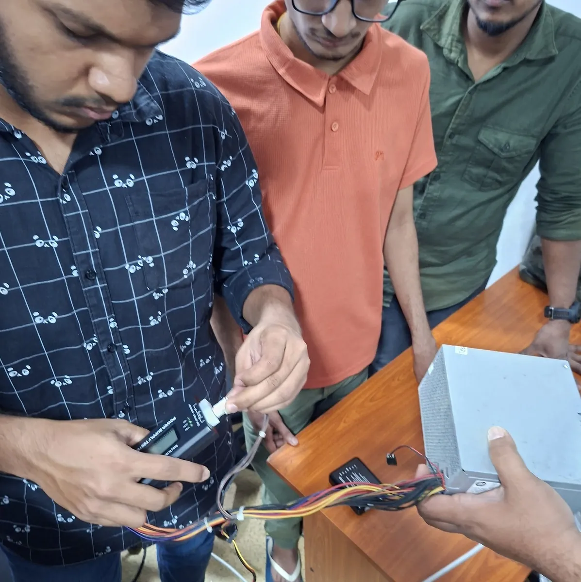 Students testing a PC power supply and internal wiring during practical training